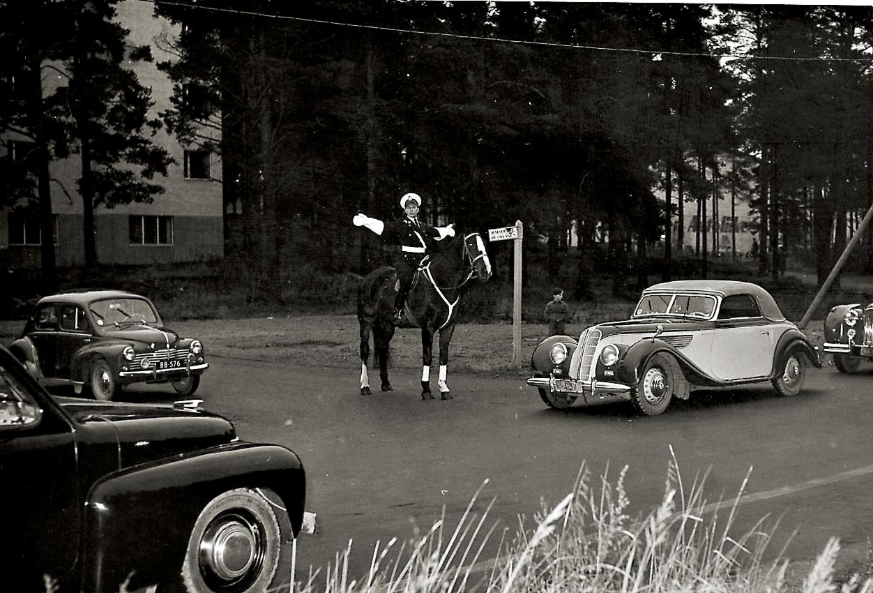 "Kas siivetönnä en voi lentää, vanki olen maan..." Ratsupoliisin ohjaamaan risteykseen ajamassa juuri BMW/EMW 327, perässään ilmeisesti Jaguar MkVIII.